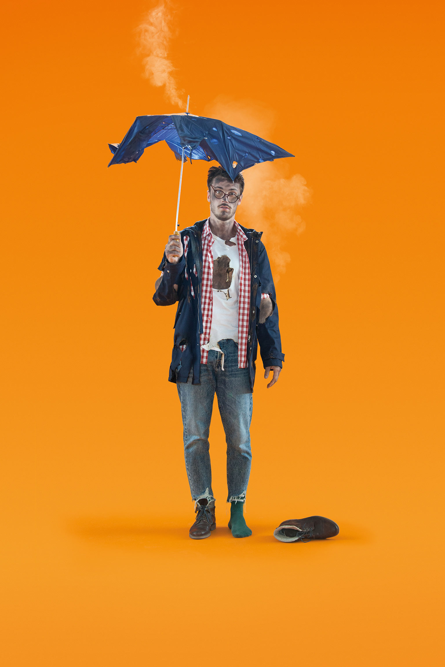 man holding a burned umbrella from a lightning strike, orange background